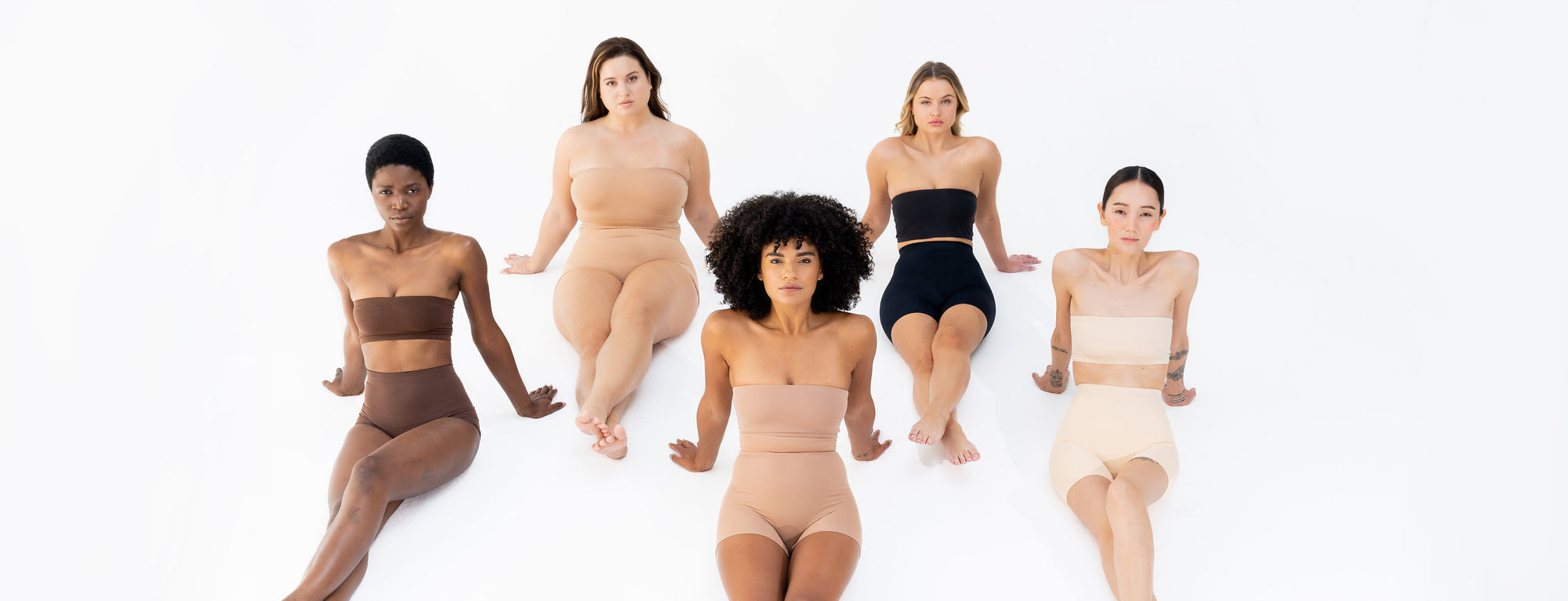 Mix race women sitting with legs crossed wearing shapewear